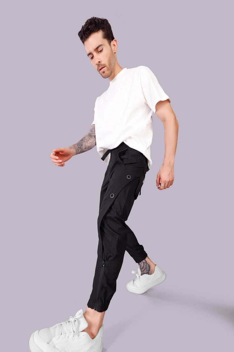 METTLE TWEED black polyester-spandex tactical cargo pants with matte black rivets and zippered ankles.