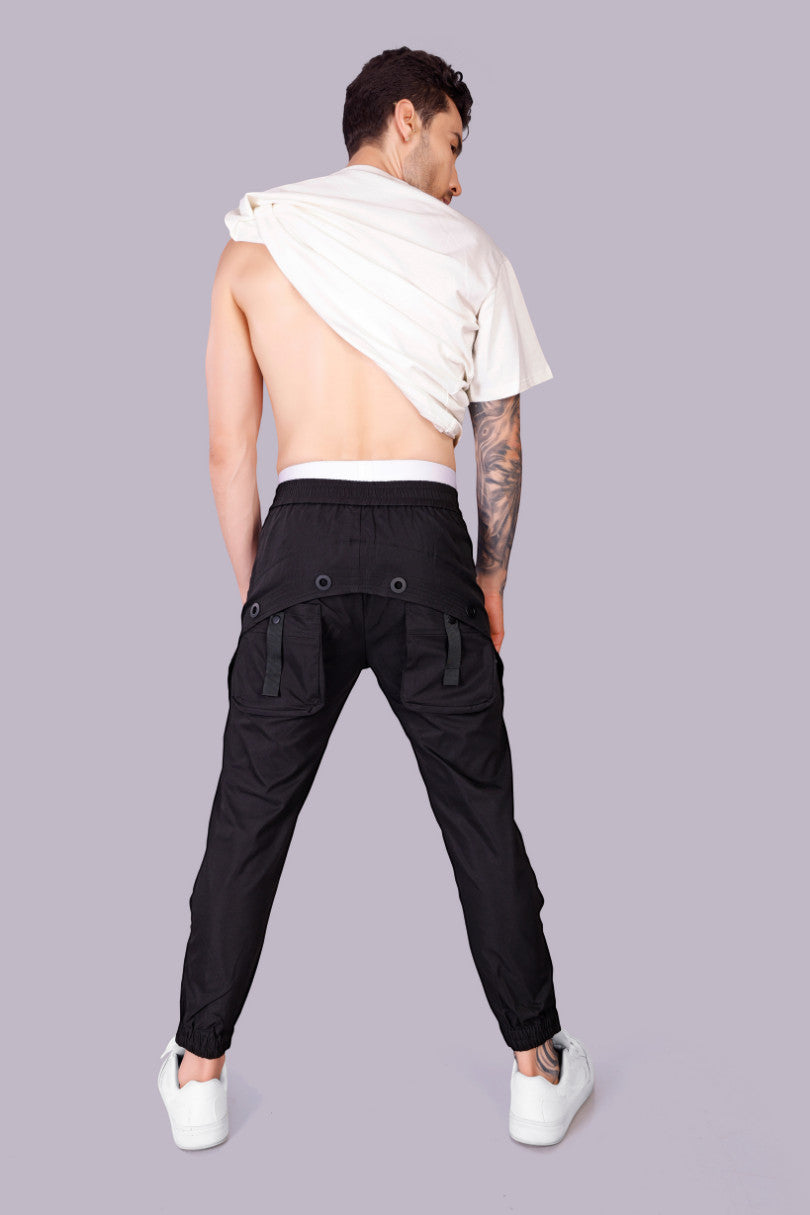 METTLE TWEED black polyester-spandex tactical cargo pants with adjustable waist and matte black rivets.