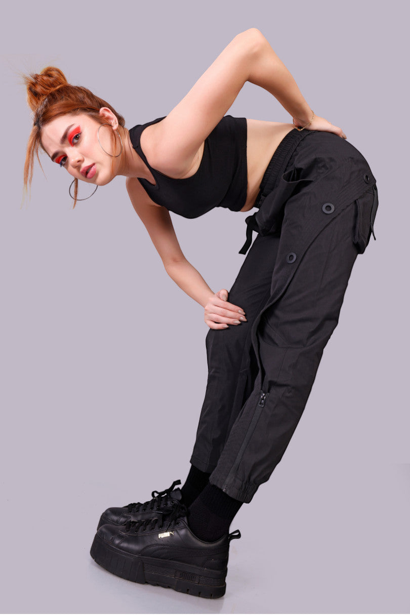METTLE TWEED black polyester-spandex tactical cargo pants with matte black rivets and zippered ankles.