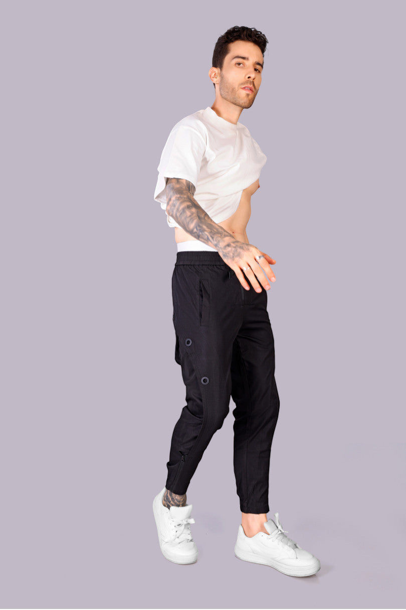 METTLE TWEED black polyester-spandex tactical pants with matte black rivets and zippered ankles.