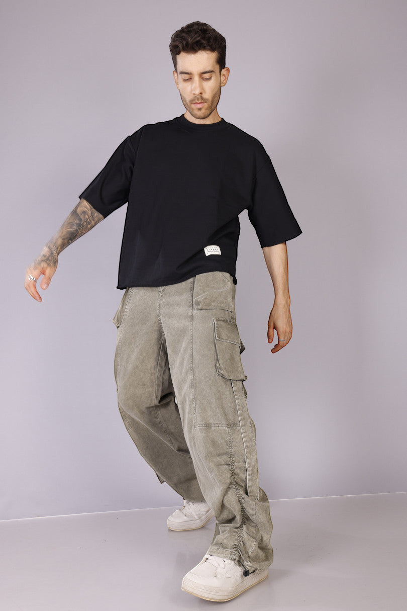 METTLE TWEED Peepal wide-leg cargo pants in washed khaki with oversized flap pockets and dangling straps.
