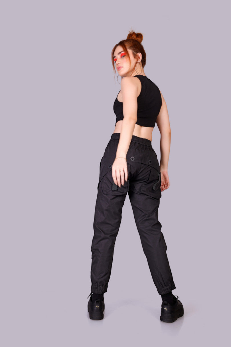 METTLE TWEED Rivettz tactical cargo pants in black polyester-spandex blend with matte black rivets and utility pockets.